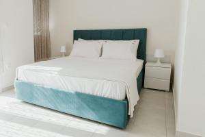 a bedroom with a large bed with a blue headboard at BLUE AND WHITE LUXURY suites in Nea Kalikratia