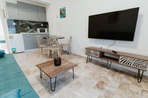 a living room with a flat screen tv on a wall at BLUE AND WHITE LUXURY suites in Nea Kalikratia