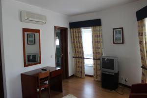 ein Wohnzimmer mit einem TV und einem Schreibtisch in der Unterkunft Hot Water Guest House in Termas de Sao Pedro do Sul