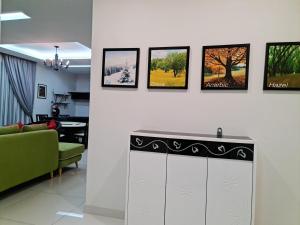 a living room with a green couch and pictures on the wall at Pearl Residences Sleep 27 in Batu Ferringhi