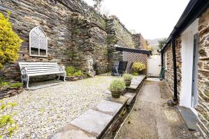 a patio with a bench and a stone wall at Ty Canol Maentwrog, Snowdonia Nr Zip World in Maentwrog