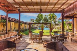 a patio with tables and chairs and a pool at Almai Cumbuco in Cumbuco