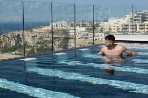 a man in a swimming pool on top of a building at Lure Hotel & Spa - Adults Only in Mellieħa