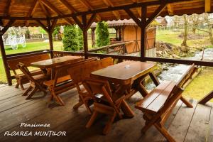 two wooden tables and chairs on a wooden deck at Pensiunea Floarea Munților in Moieciu de Sus