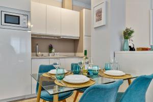 a dining room with a glass table and blue chairs at Coral Apartment La Cala Beach in La Cala de Mijas