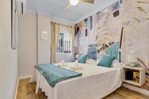 a bedroom with a large white bed with blue pillows at Coral Apartment La Cala Beach in La Cala de Mijas