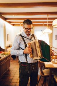 a man holding an accordion in a kitchen at Pension Baranek - Baranek Resorts in Kaprun +54 photos