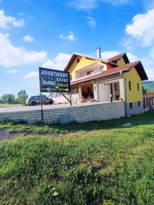 a sign in front of a building with a house at Apartments & Rooms Ramljak in Korenica