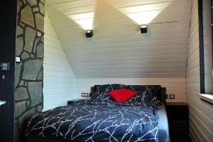 um quarto com uma cama com uma almofada vermelha em Domki u Biesiady em Lesko