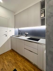 una cocina con armarios blancos y fregadero en Tarvisio City House, en Tarvisio