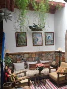 a living room with couches and paintings on a wall at Riad Dar Latifa in Essaouira
