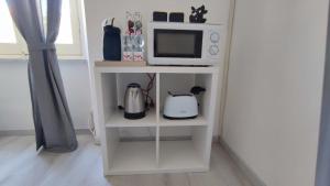ein kleines weißes Regal mit einer Mikrowelle und einer Mikrowelle in der Unterkunft Leo Holiday Homes in Deiva Marina