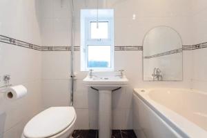 a bathroom with a toilet and a sink and a tub at Charming Cottage 4 Bedroom in Acton