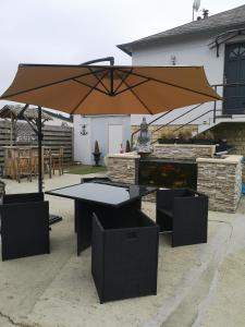 eine Terrasse mit einem Sonnenschirm, einem Tisch und Stühlen in der Unterkunft La maison du bonheur in Port-en-Bessin-Huppain