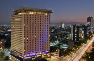 un grand bâtiment dans une ville la nuit dans l'établissement Fiesta Americana Reforma, à Mexico