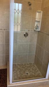 a shower with a glass door in a bathroom at La Capucine in Kroonstad