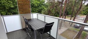 einen Balkon mit einem Holztisch und 2 Stühlen in der Unterkunft Apartament rodzinny w obiekcie Nautikka Park in Krynica Morska