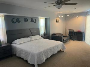 a bedroom with a bed and a chair and a ceiling fan at Melody 3-Bedroom Pool Villa close to the beach!!! in Port Charlotte