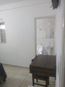 La salle de bains est pourvue d'une table, d'un lavabo et de toilettes. dans l'établissement Hotel Iguaçu, à Botucatu