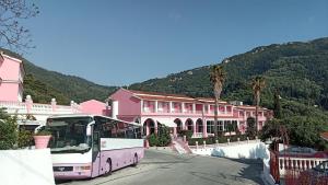 a pink bus parked in front of a pink building at Pink Palace Beach Resort in Agios Gordios