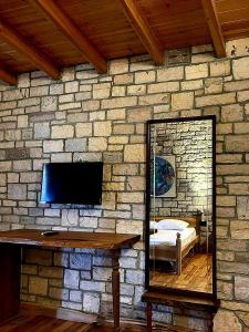 a mirror on a stone wall with a television at Palermiti Luxury Rooms in Himare