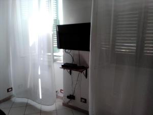a television sitting in a room with a curtain at Casina del porto in Livorno