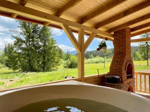a hot tub in a porch with a fireplace at Cabana Katica vendégház in Borzont