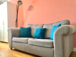 a couch with blue pillows in a living room at Lovely Studio Room in the heart of Kingston upon Thames in Kingston upon Thames