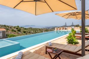 a pool with an umbrella and some chairs and a table at Vidikovac Levanda Luxury Apartments in Hvar