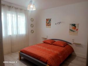 a bedroom with a bed with red sheets and a window at Le petit Cosy in Saint-Laurent-de-la-Salanque