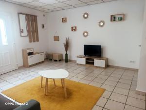 a living room with a table and a tv at Le petit Cosy in Saint-Laurent-de-la-Salanque