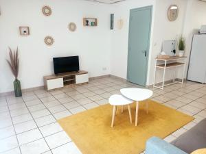 a living room with two white chairs and a tv at Le petit Cosy in Saint-Laurent-de-la-Salanque