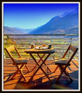 einen Tisch und zwei Stühle auf einer Terrasse mit Aussicht in der Unterkunft Atmosfera e vista mozzafiato Chalets in Aosta