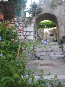 une arche dans un mur en pierre avec des escaliers et des fleurs dans l'établissement Guesthouse Villa Galovic, à Brseč