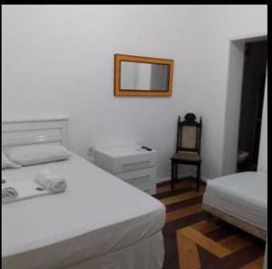 a bedroom with two beds and a mirror and a chair at Hotel Pousada Brisa Mar in Salvador