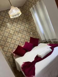 a bedroom with a bed with red pillows and a chandelier at Estalagem Meu Sonho in Penedo