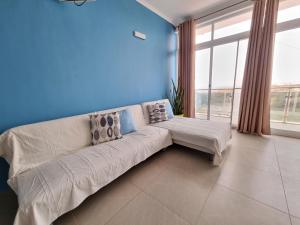 Appartement Cara do Mar في برايا: غرفة معيشة مع أريكة بيضاء وجدار أزرق