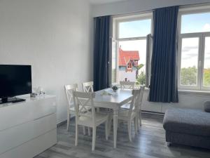 ein Esszimmer mit einem Tisch, Stühlen und einem TV in der Unterkunft Modern House Gehrden 2 in Gehrden