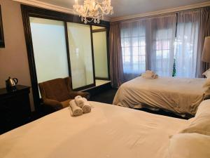 ein Hotelzimmer mit 2 Betten und einem Stuhl in der Unterkunft Halfway House Hotel in Kimberley