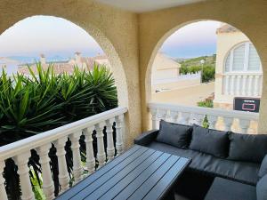 a porch with a bench and a balcony with arches at Casa Azure in Gran Alacant