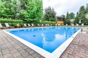 una piscina con sillas y agua azul en Townhouse With Free Shuttle To Tremblant Resort en Mont-Tremblant