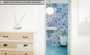 baño con azulejos azules y reloj en la pared en Zagma Un Passo Dal Mare en Canneto