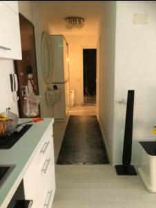 una cocina con un pasillo que conduce a una cocina con armarios blancos en Lovely 2 bedroom condo in Gjilan., en Gnjilane
