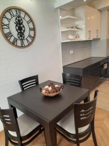 a dining room table with chairs and a clock on the wall at Apartman NK in Nikšić