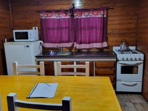 a kitchen with a table and a stove and a window at Cabañas Los Acacios Complejo Lobos in Lobos