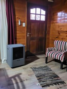 a room with a television and two chairs and a door at Cabañas Los Acacios Complejo Lobos in Lobos