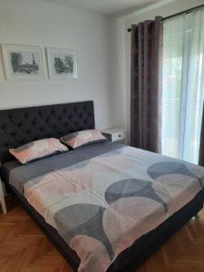 ein großes Bett in einem Schlafzimmer mit Fenster in der Unterkunft Apartman NK in Nikšić