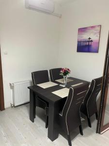a black table with chairs and a vase of flowers on it at Patrik Deluxe in Gyula