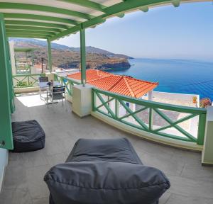 a balcony with a view of the ocean and a house at Corali Suites Andros in Batsi