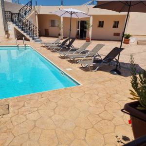 a swimming pool with lounge chairs and an umbrella at Potamos Private Suites in Paphos City